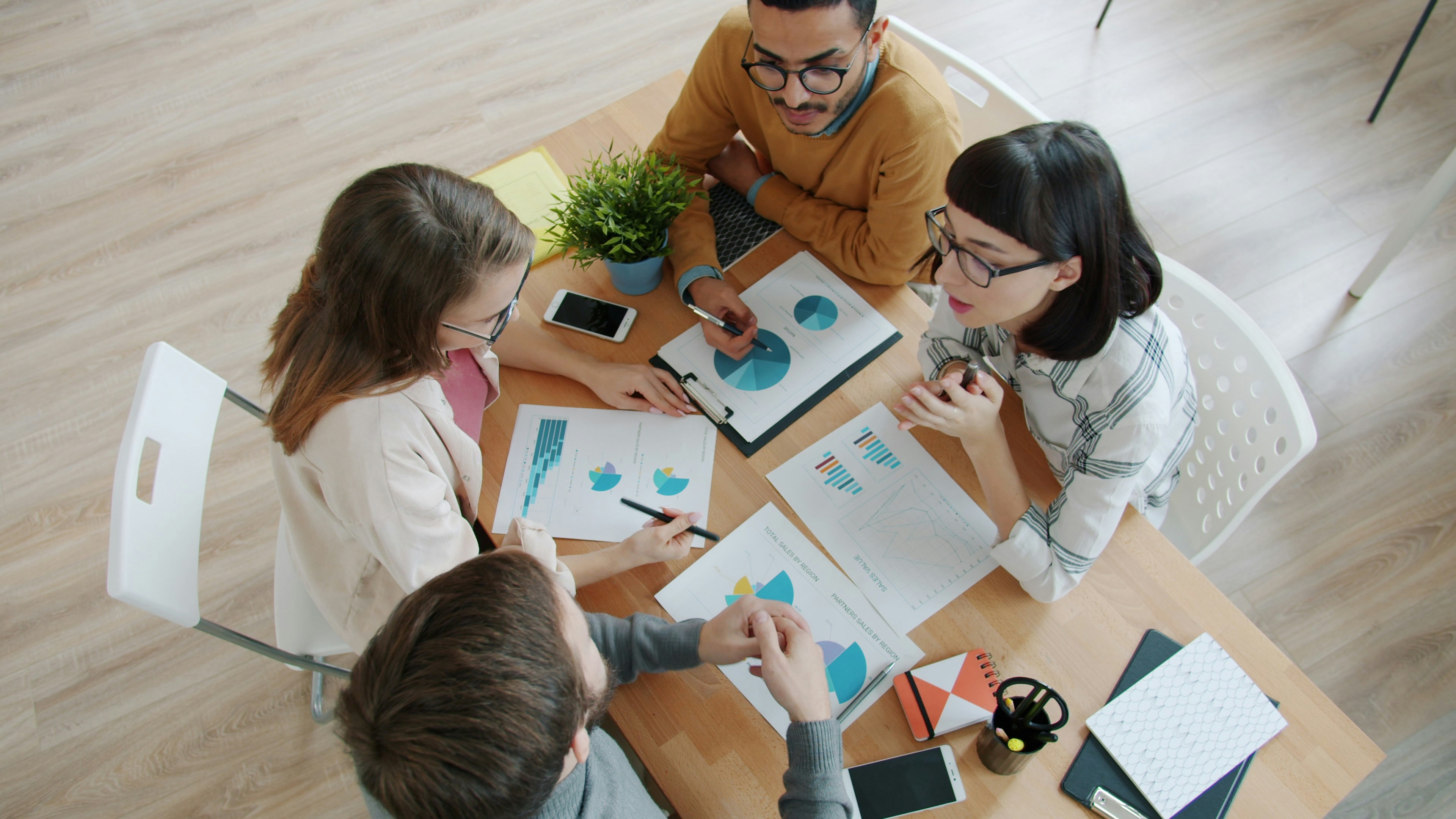 A team gathered around a table reviewing financial charts and discussing strategy together.